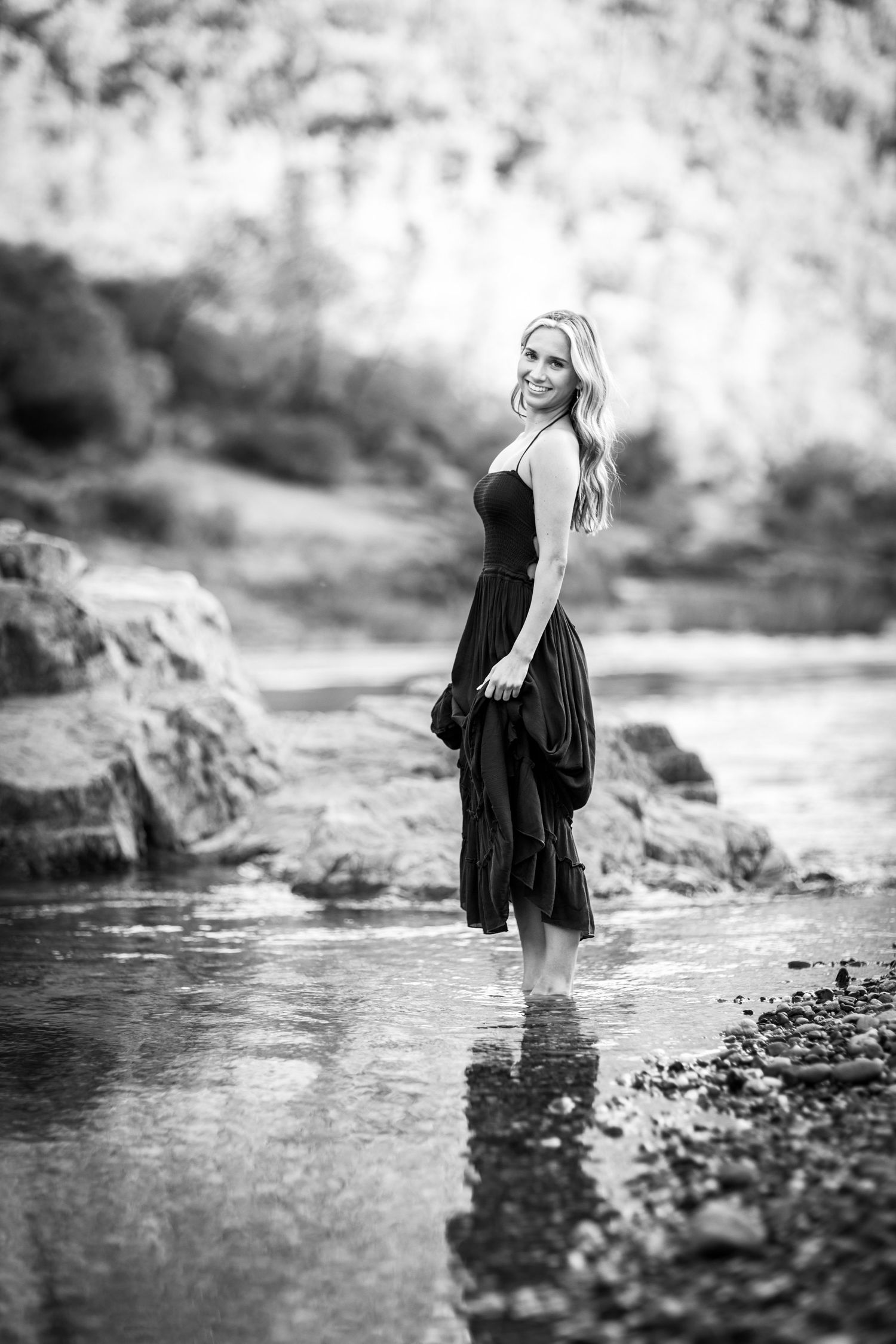 Artistic black and white portrait session by a rocky waterfront.