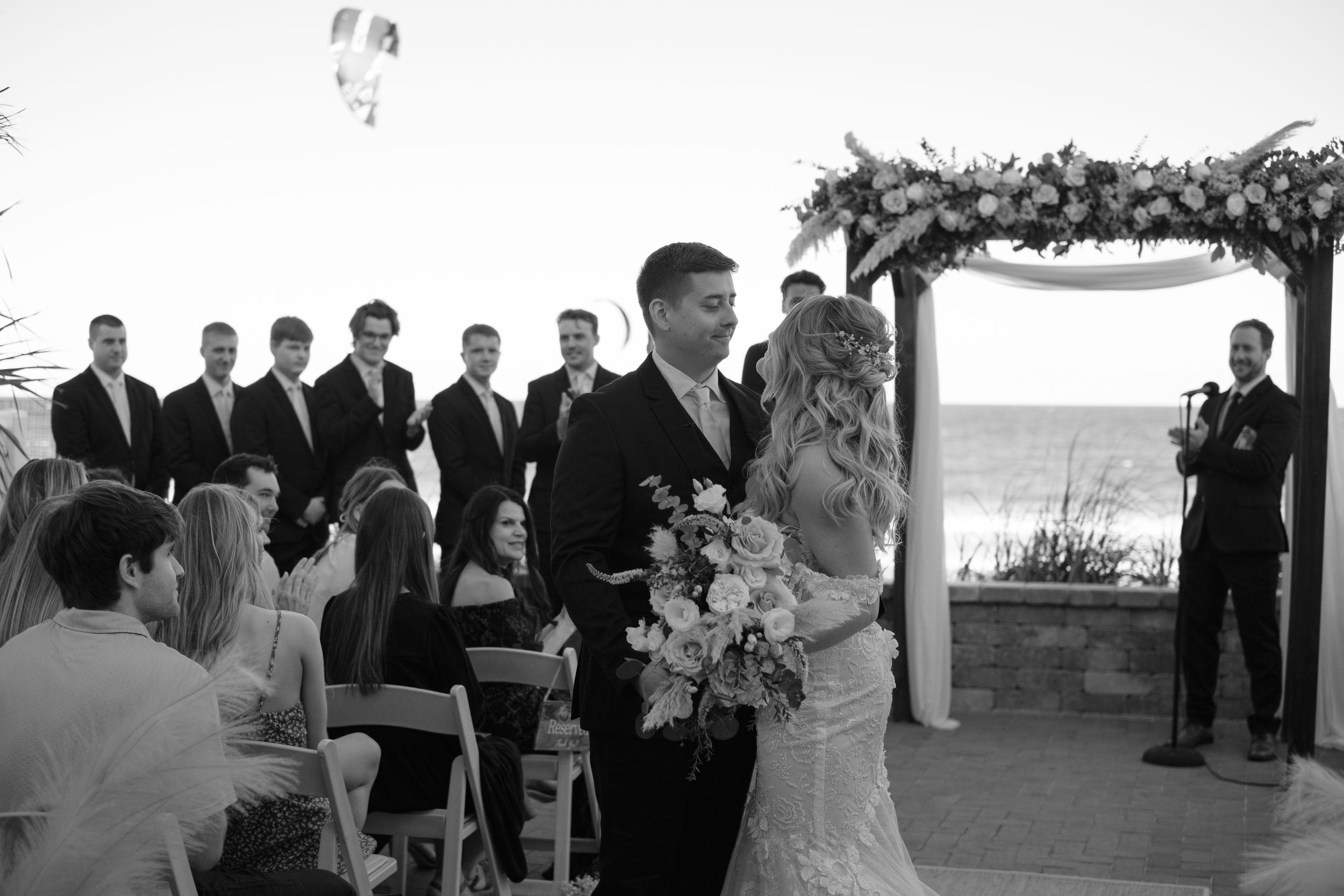 Moments after a couple is married with a candid moment of someone parasailing in the background