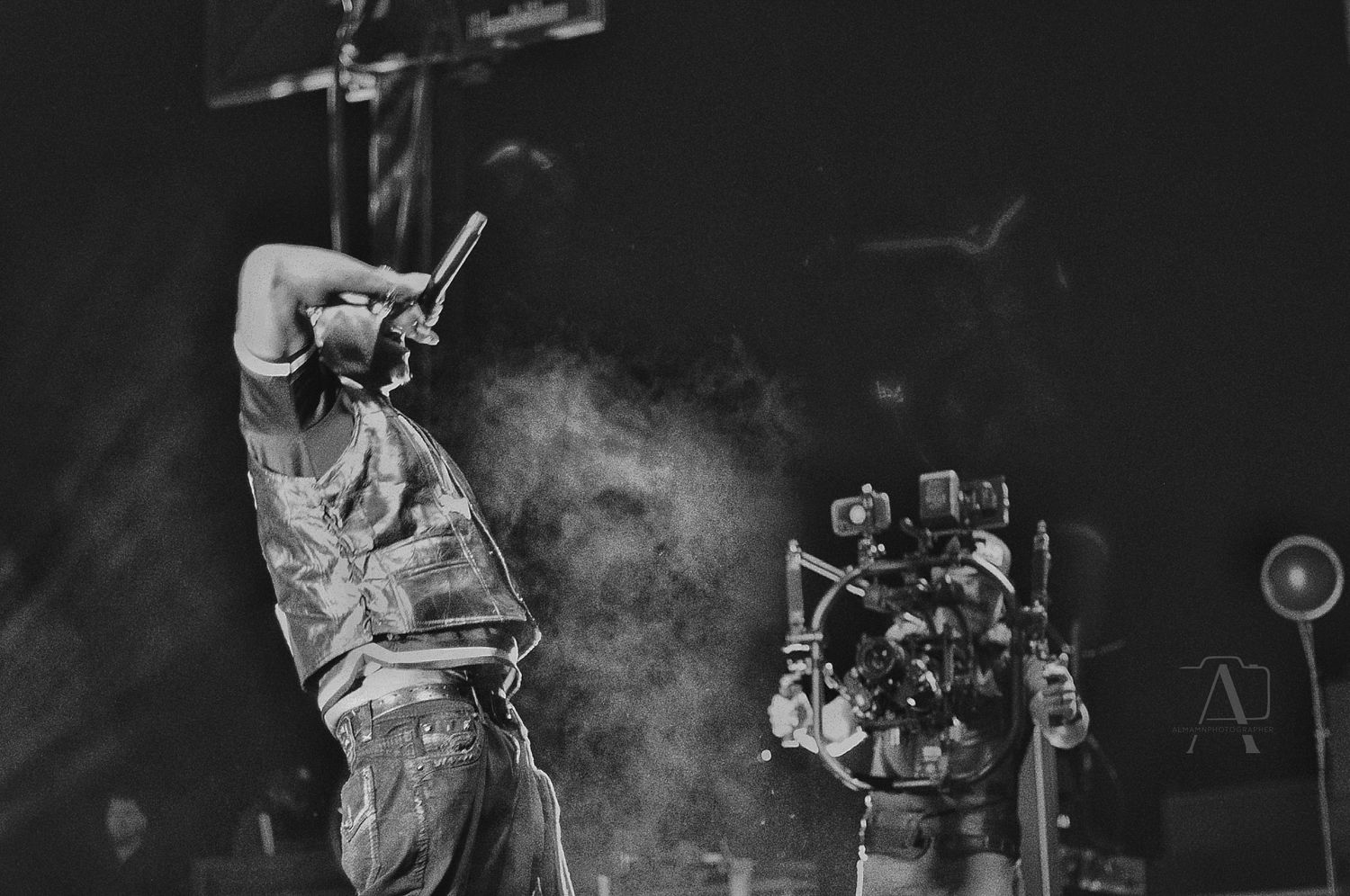 Black and white concert photo capturing performer in action with atmospheric stage smoke.