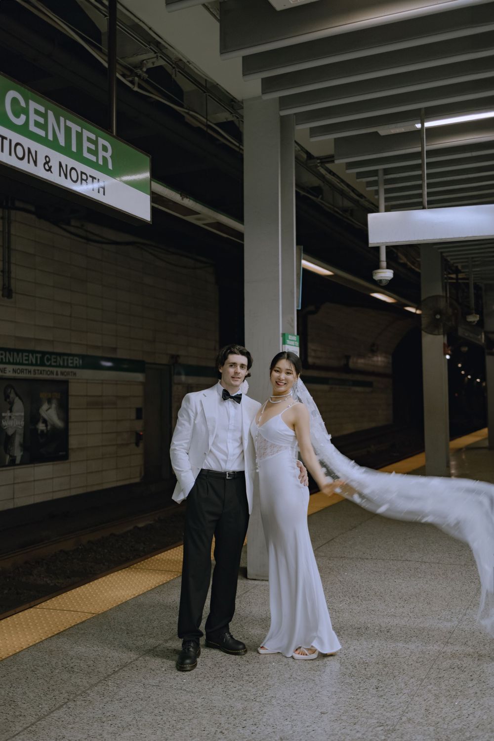 Wedding couple posing and dancing in subway station with Government Center sign visible.