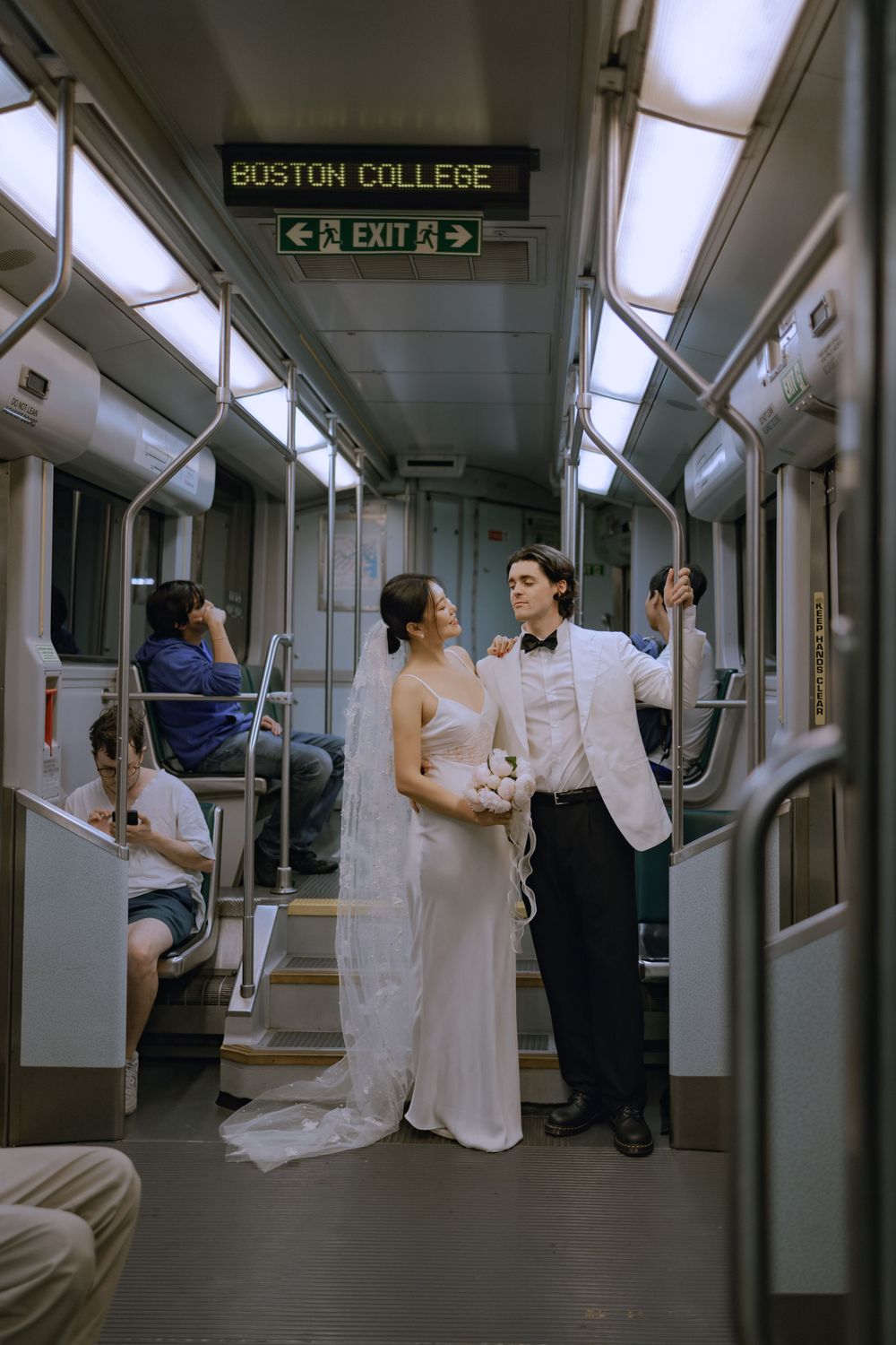 Wedding couple playfully interacting inside Boston College subway car.