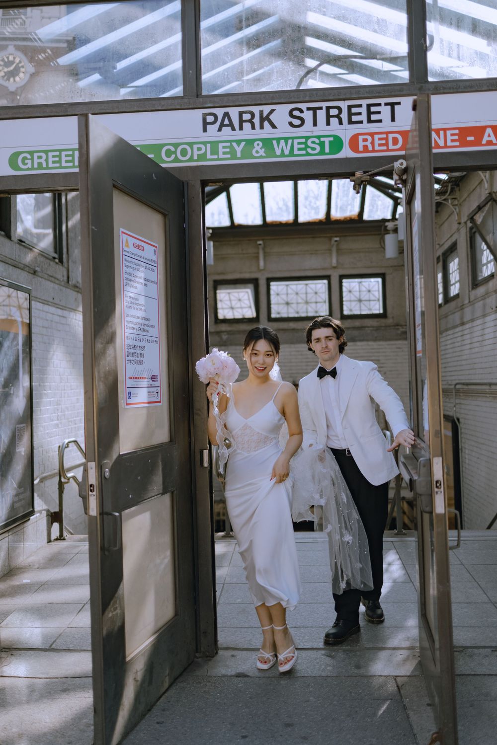 A couple in wedding attire walks through Park Street subway station in Boston.