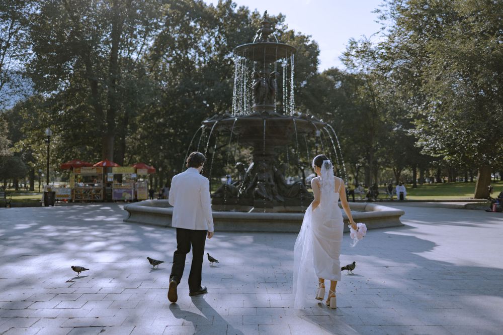 Wedding couple walking together on a sunny outdoor plaza.