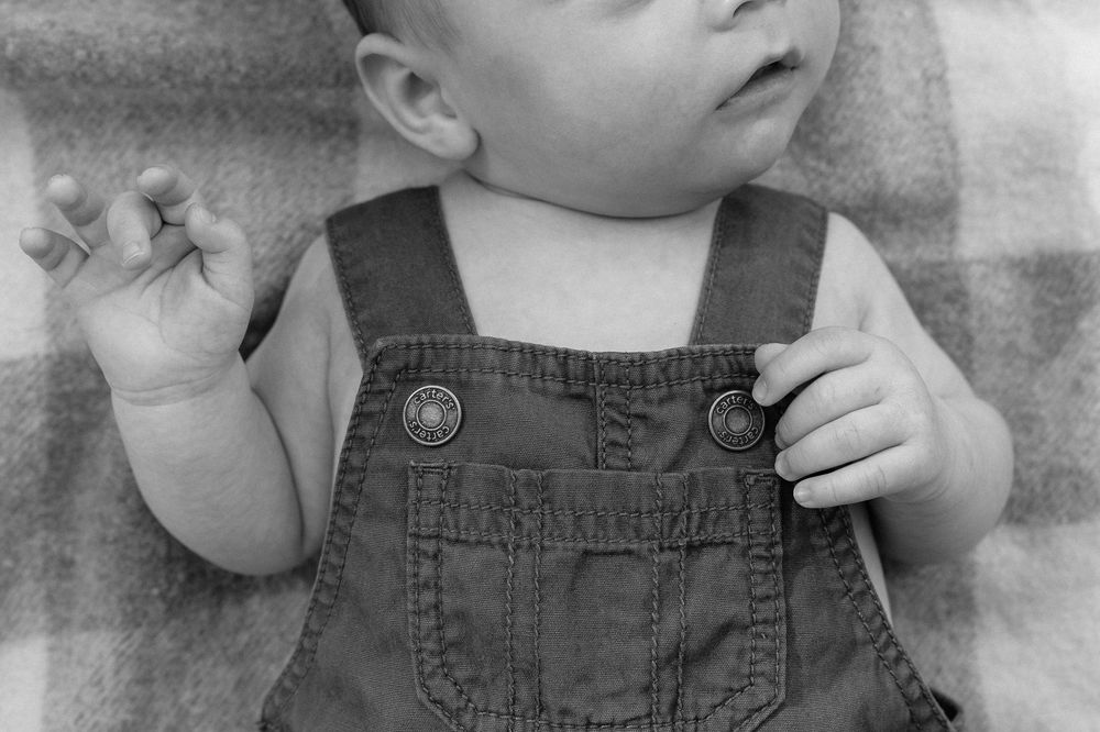 Four black and white photos showing similar poses of a child wearing denim overalls against a light background.