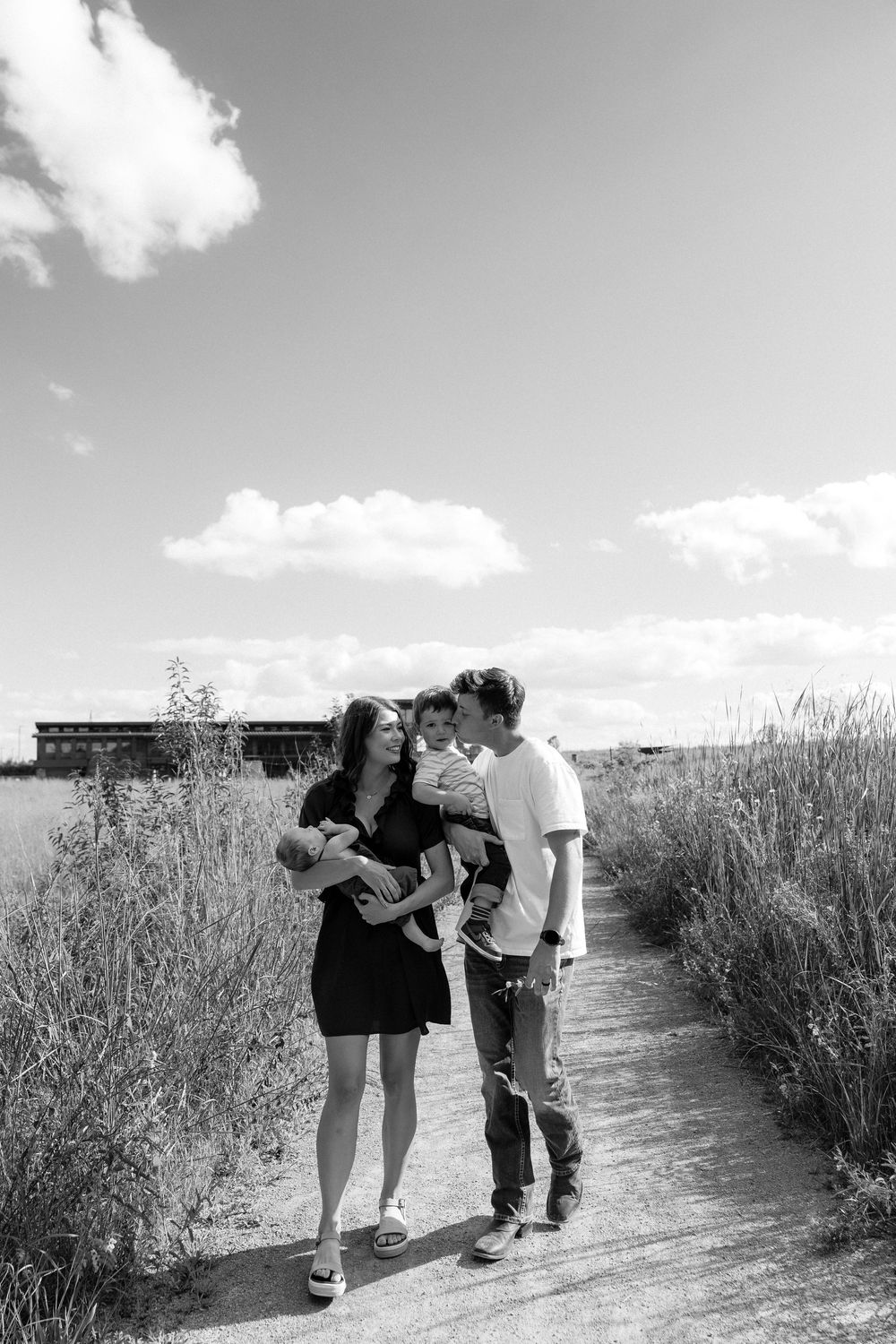 A series of monochrome photos showing people bending down to observe or photograph something along a nature trail.