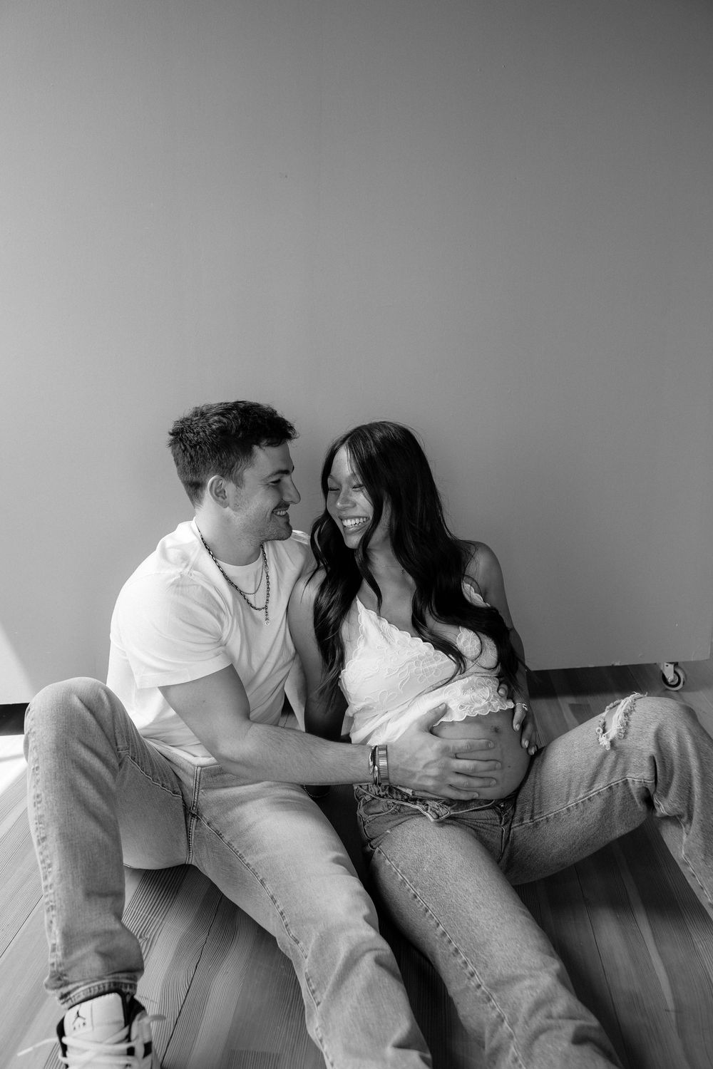 A black and white photo series showing a couple in casual clothing laughing and relaxing together on a couch.