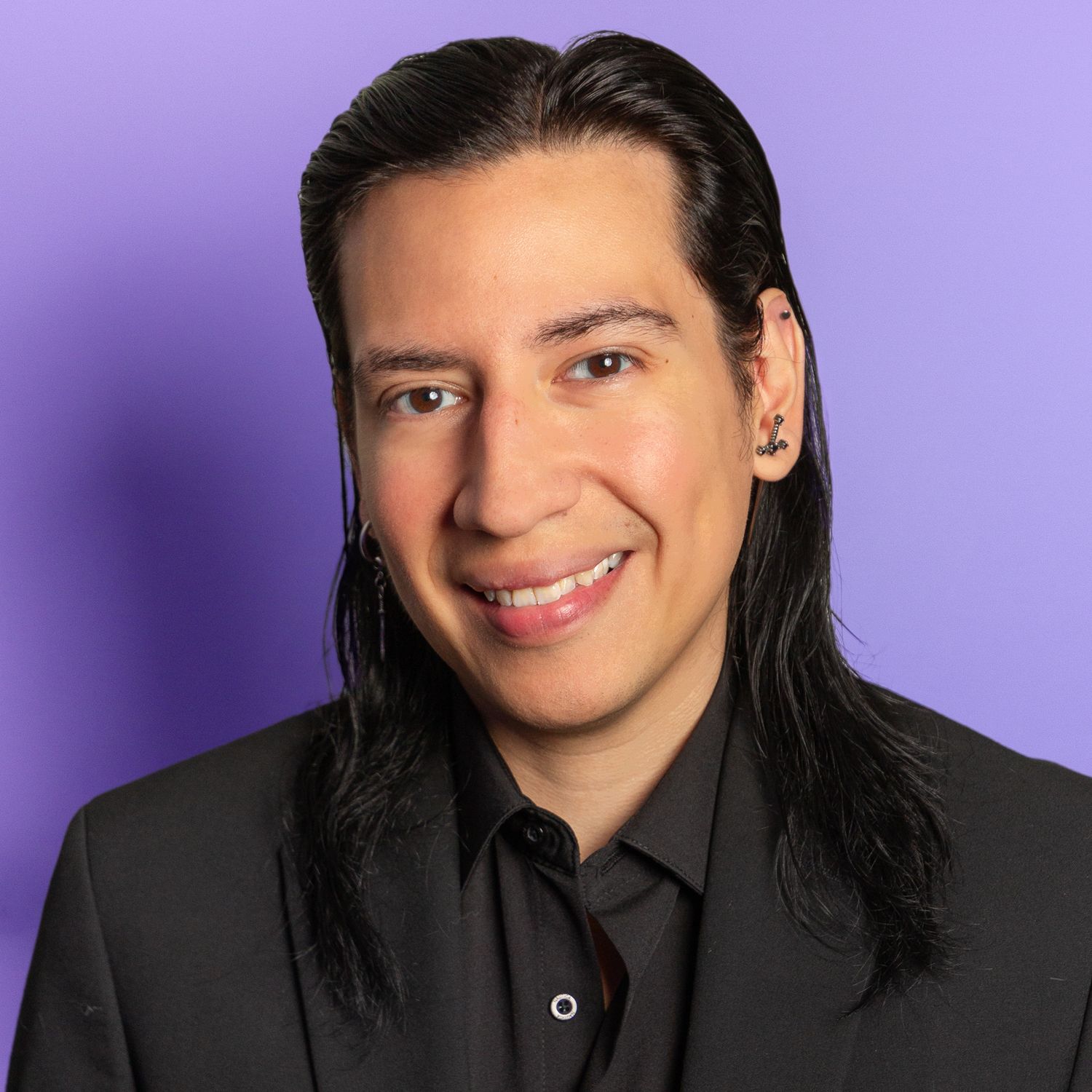 Professional studio headshot against purple background wearing black shirt and long dark hair.