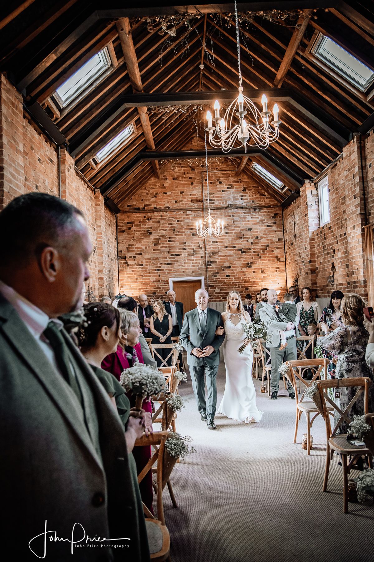 Wedding ceremony in a rustic brick venue with exposed beams and chandeliers.