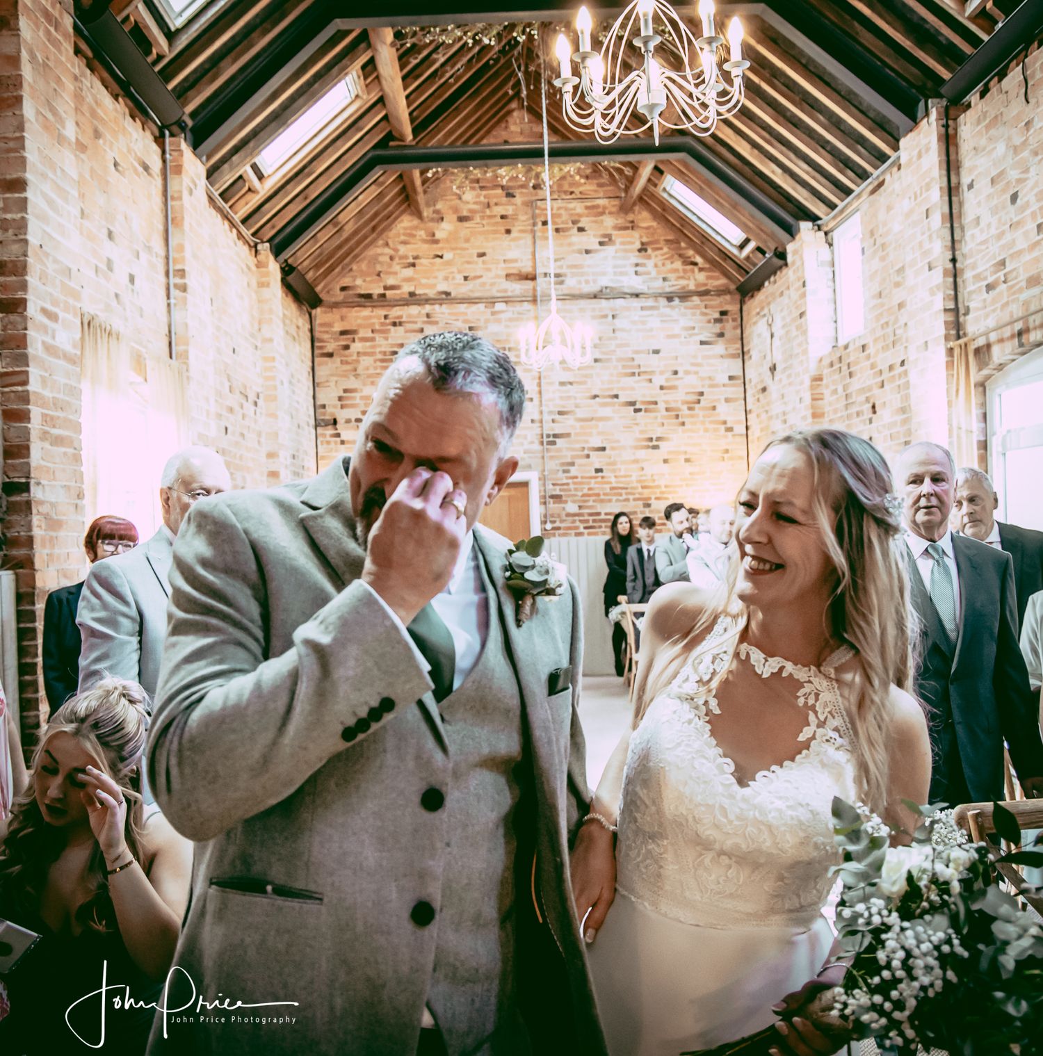 Emotional moment captured in a rustic brick ceremony venue with natural lighting.