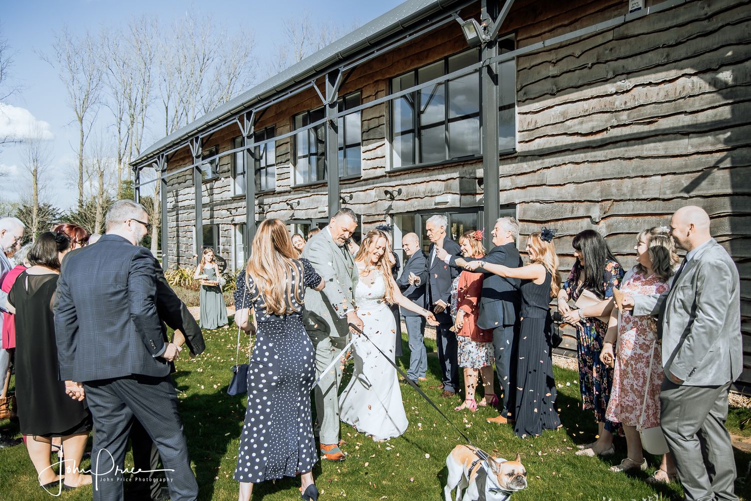 Wedding guests gathered outside a rustic wooden venue during an outdoor celebration.