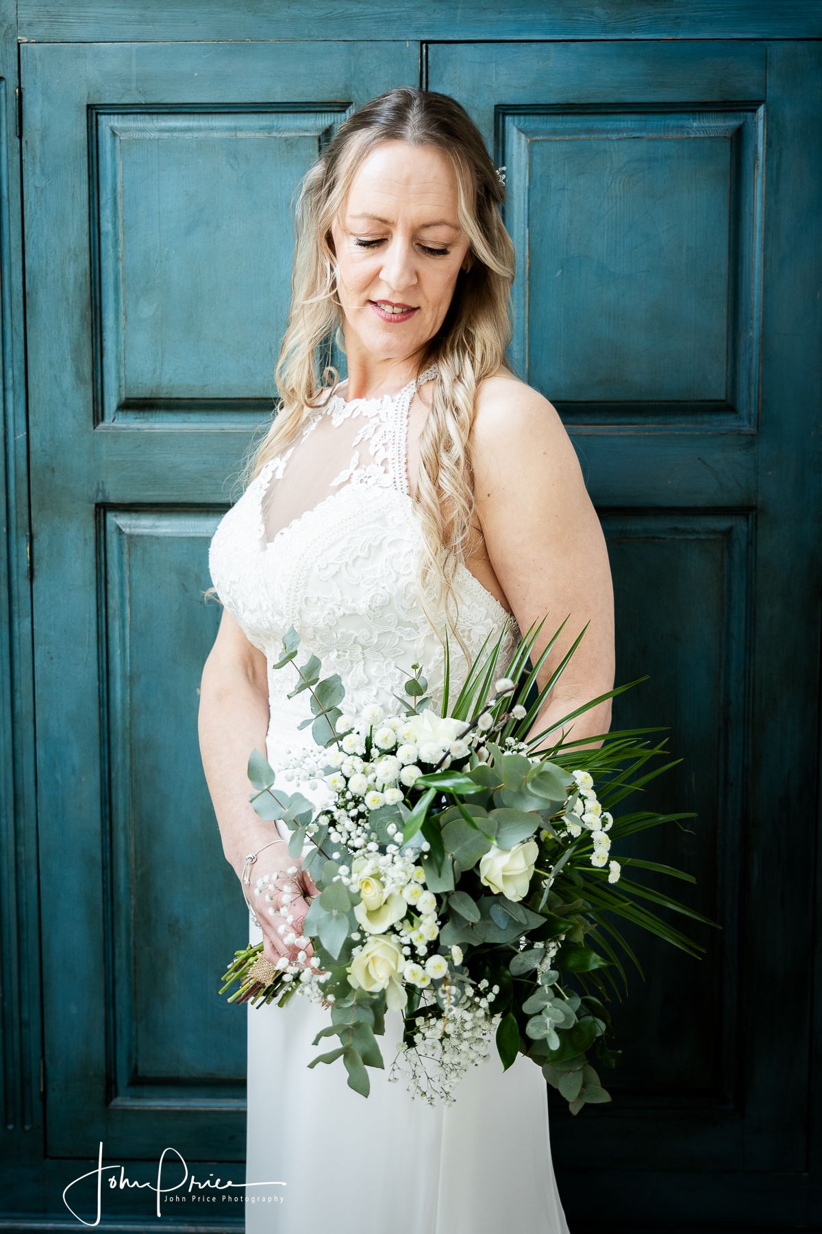 A bridal portrait with white floral bouquet against a teal blue door.