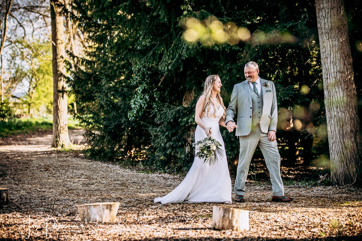 Couple posing for wedding photos in a wooded area with lanterns and romantic lighting.