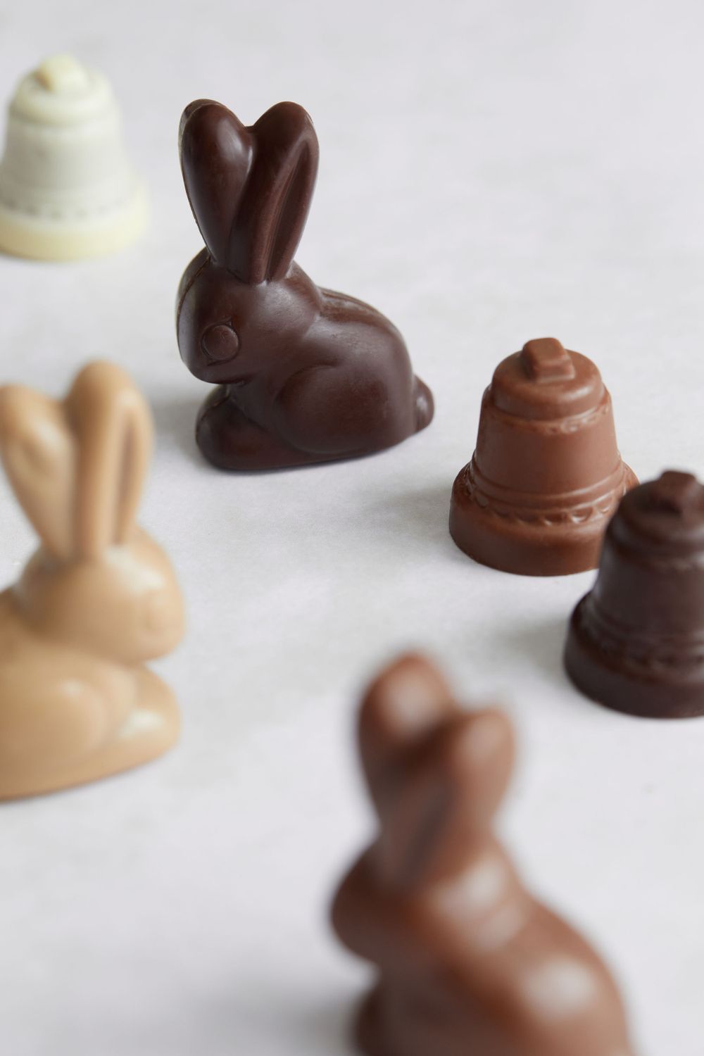 Dark and milk chocolate bunny figures and bell-shaped candies displayed on white background.
