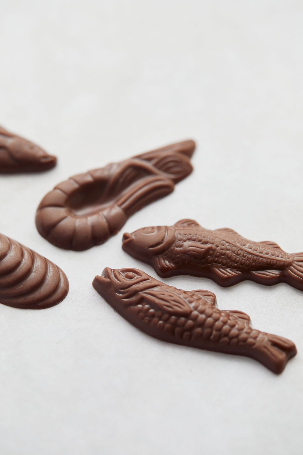 Chocolate seafood-shaped confections arranged on white surface with detailed fish patterns.