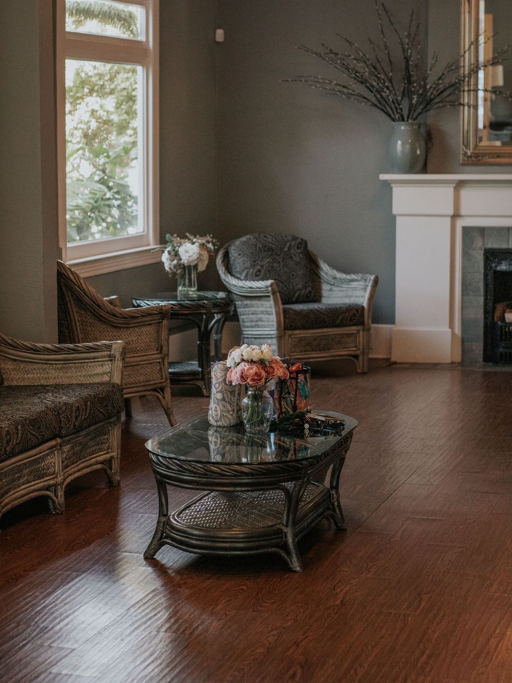 Cozy living room corner with wicker furniture, hardwood floors and decorative fireplace.