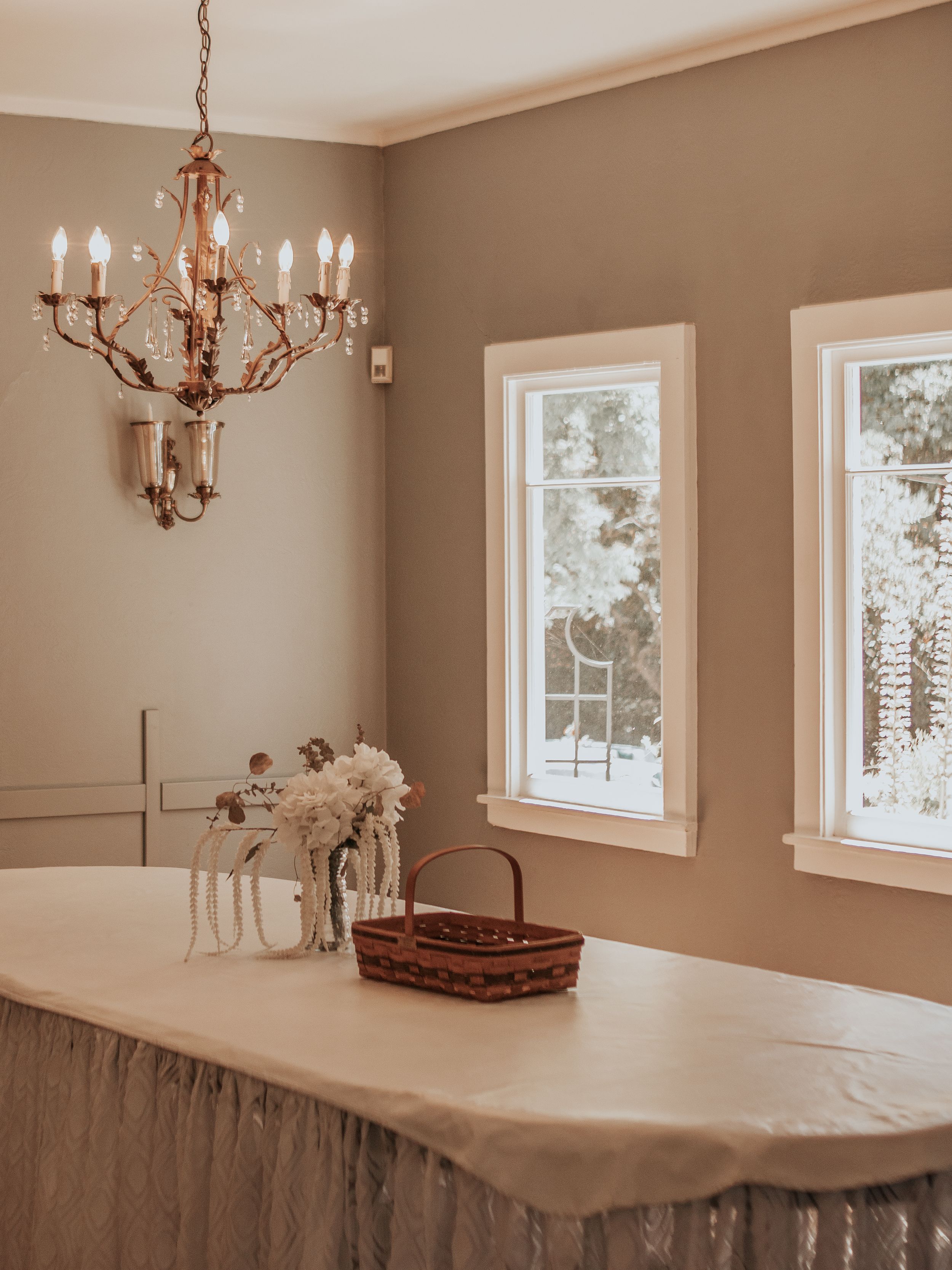 Elegant dining room with chandelier, white windows, and neutral taupe walls.