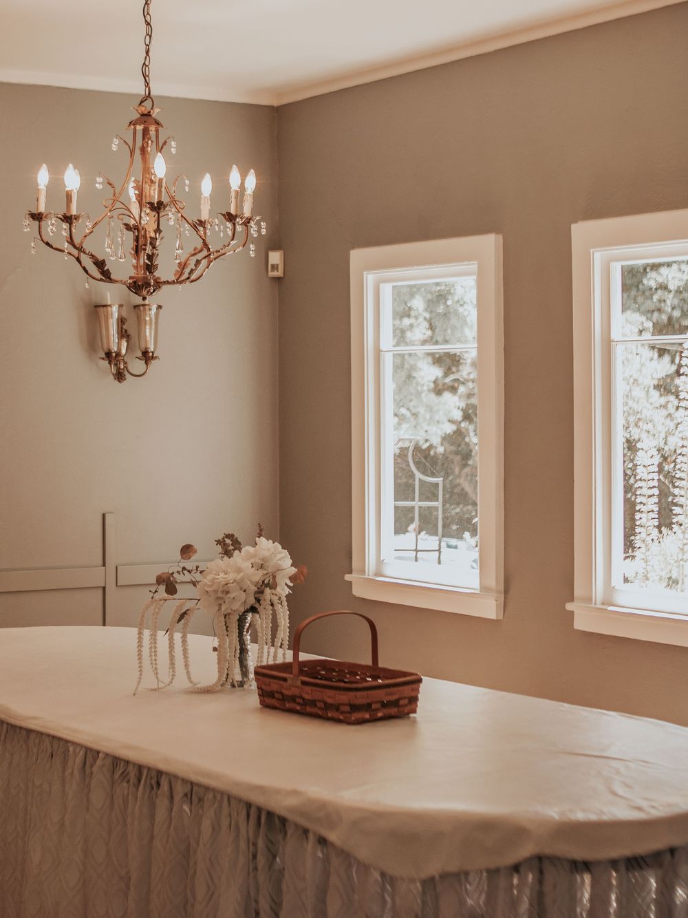 Elegant dining room with chandelier, white windows, and neutral taupe walls.