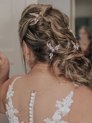 Intricate bridal hairstyle with crystal accessories and delicate lace dress detail.