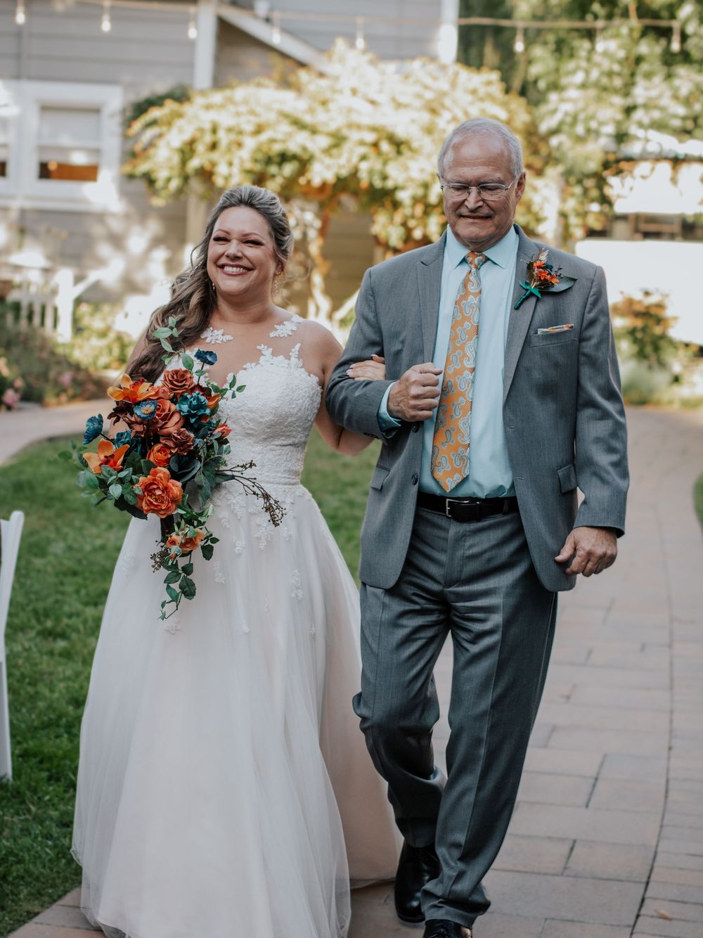 Wedding photo showing a walk down a garden path with colorful autumn bouquet.