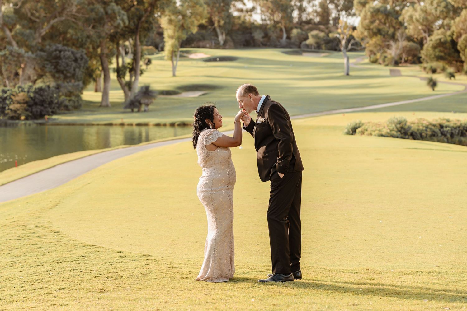 Outdoor garden wedding ceremony with white chairs and floral arch as couple exits down aisle.