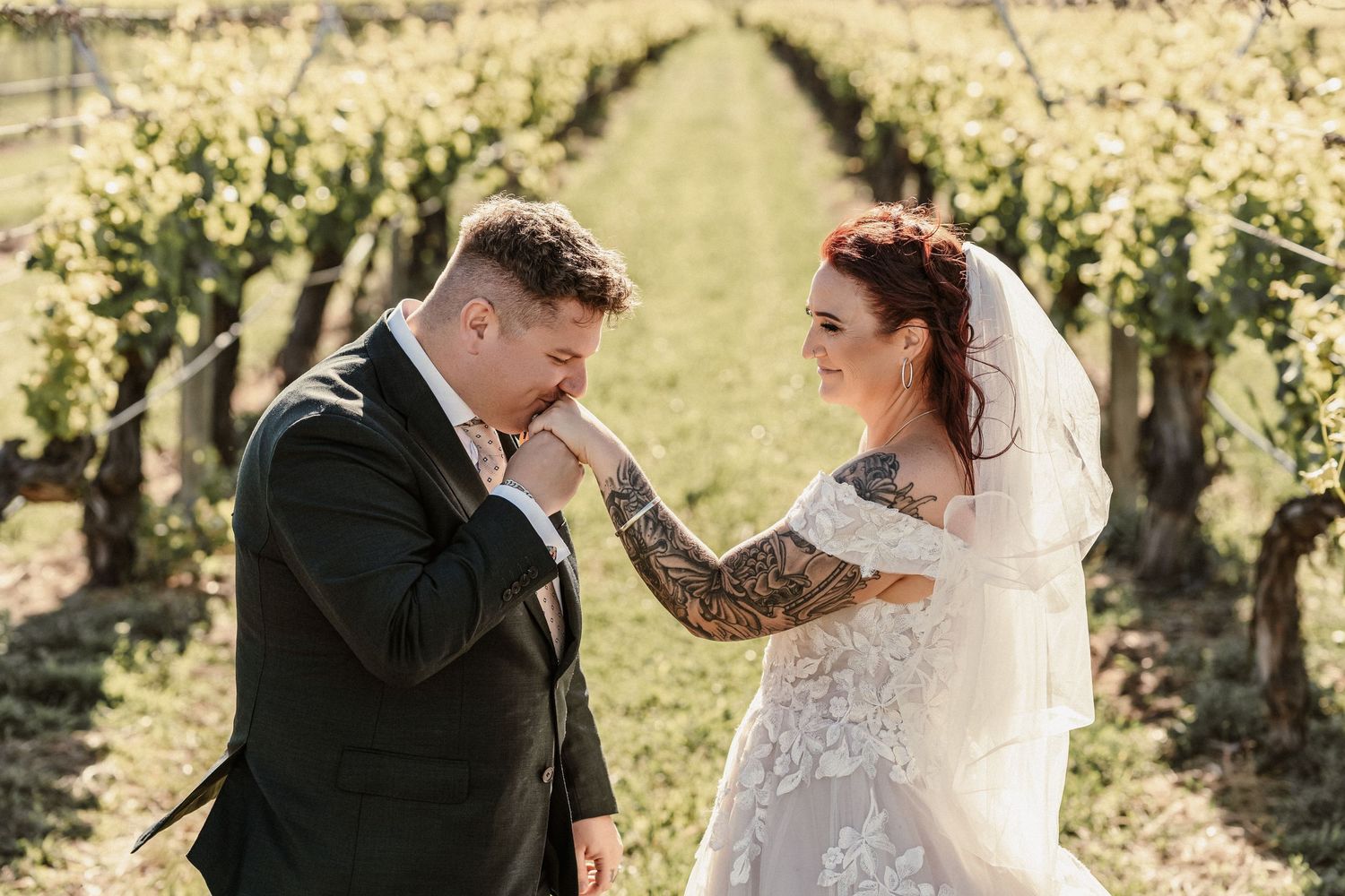 Outdoor garden wedding ceremony with white chairs and floral arch as couple exits down aisle.