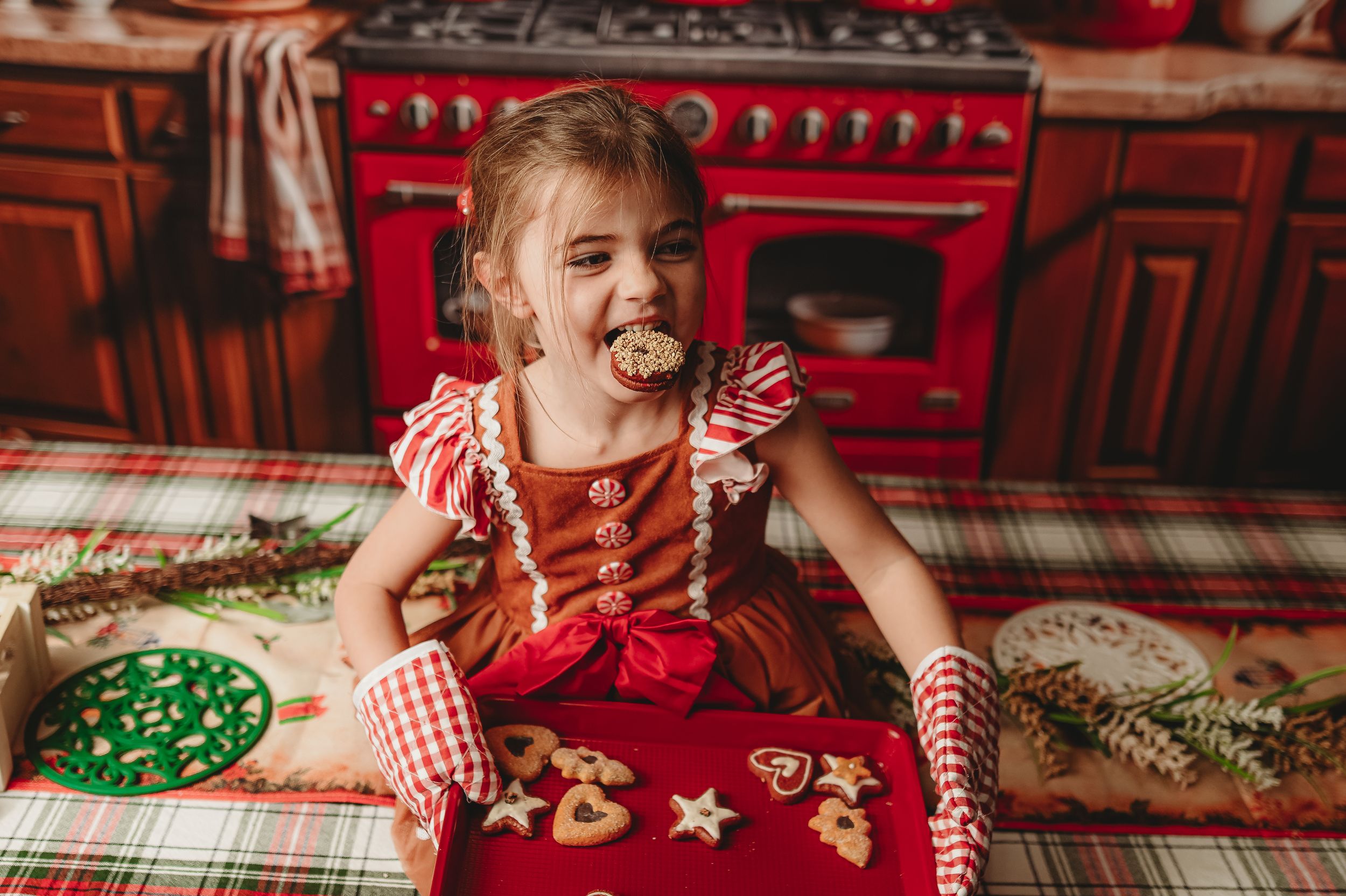 Christmas cookie decorating setup in rustic kitchen with red vintage stove and brick walls.