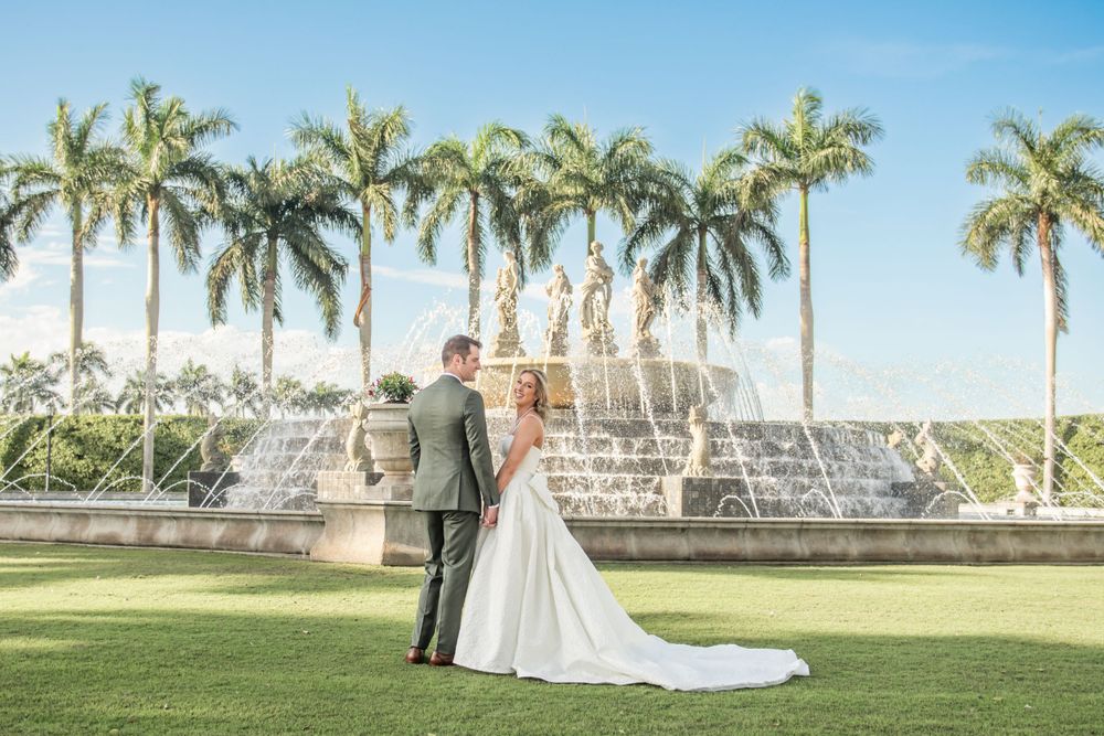 bride and groom posing at their venue in front of waterfall and palm trees in Florida