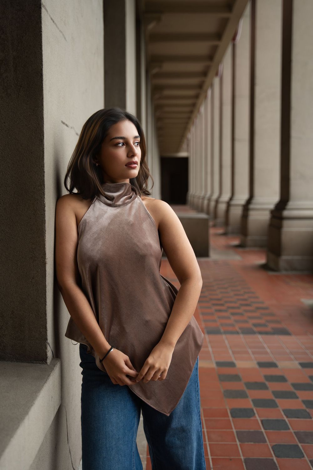 Fashion portrait in hallway with dramatic lighting showcasing casual outfit against vintage architecture.