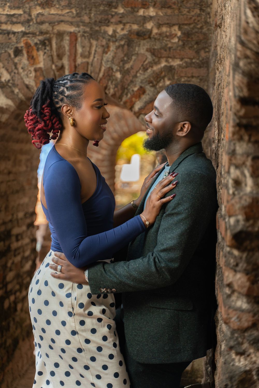 A couple shares an intimate moment against a rustic brick wall background in a series of romantic poses.