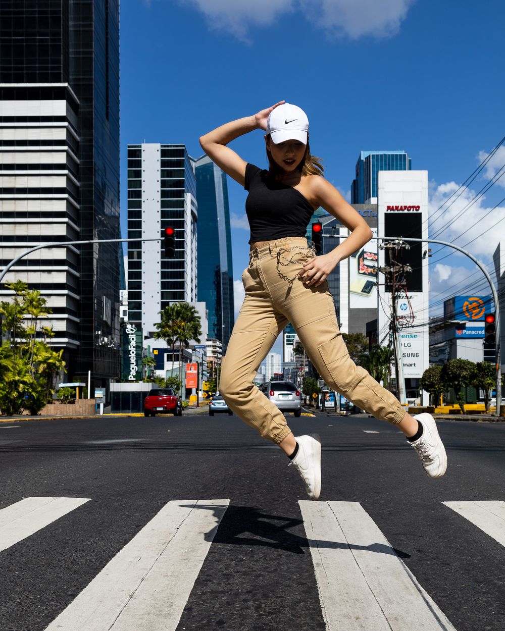 A sequence of five photos showing a person in khaki pants jumping across a crosswalk in an urban setting with tall buildings.