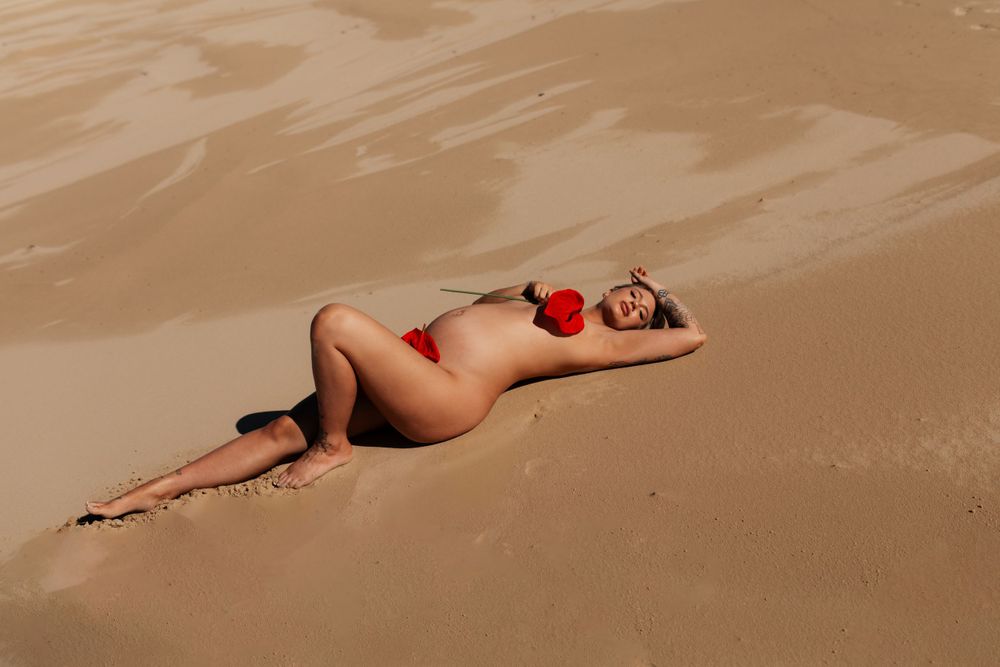 Artistic photo of woman lying on desert sand with red apple.