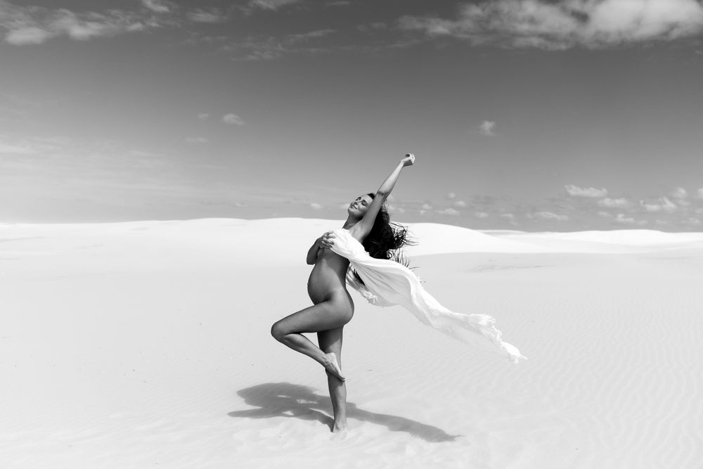 Professional figure skater performing an elegant spin with extended arms on ice in black and white photography.