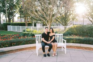 Couple sitting together on white Adirondack chairs in a garden setting during golden hour.