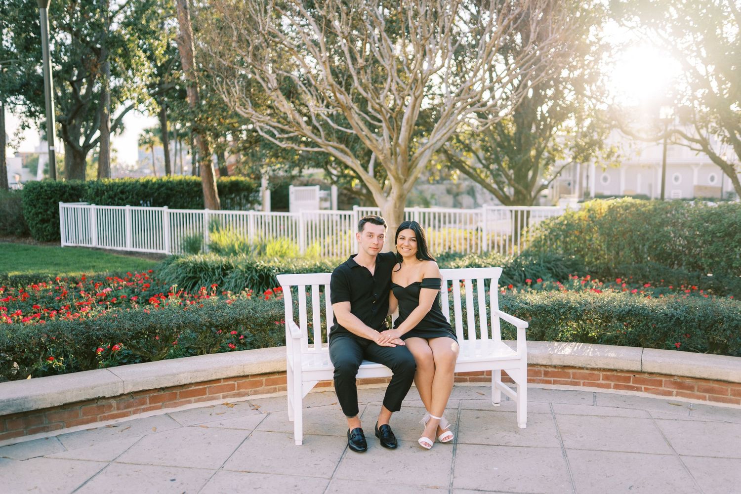 Couple sitting together on white Adirondack chairs in a garden setting during golden hour.