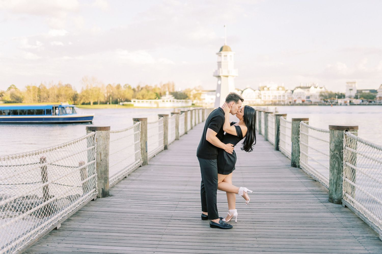 A couple embraces on a scenic waterfront boardwalk during a romantic moment.