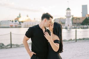 Couple in black outfits sharing romantic moments during sunset photoshoot on beach.