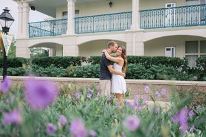 Couple embraces in a romantic garden setting with purple wildflowers blooming in the foreground.
