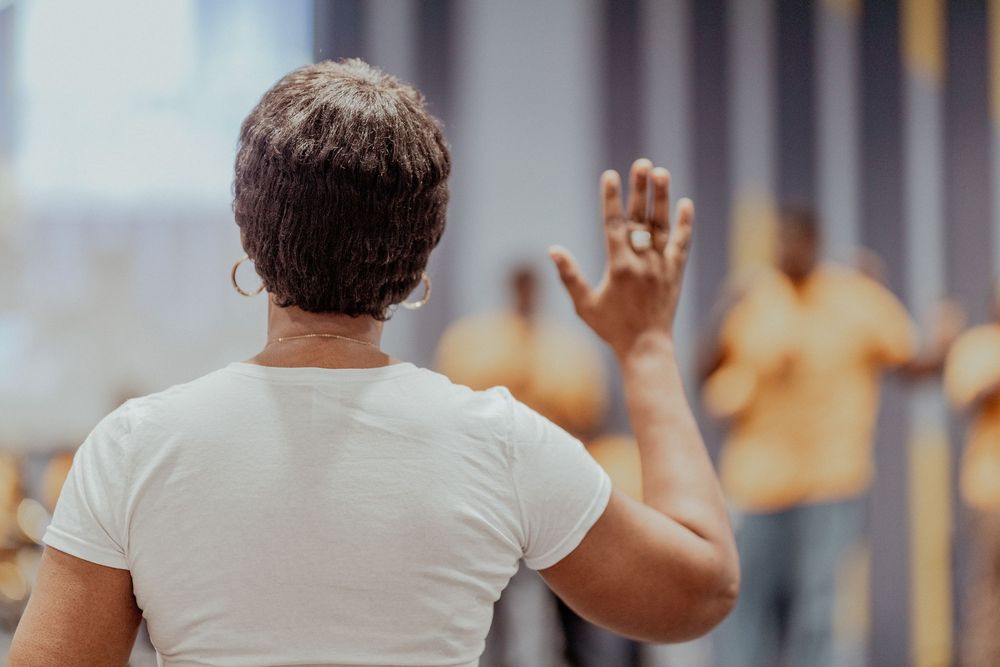 People practicing yoga in a bright studio with wooden floors and white walls during a group fitness class.