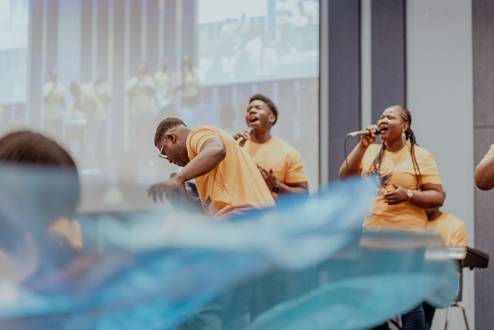 Group of people dancing and moving energetically in a dance studio with large windows.