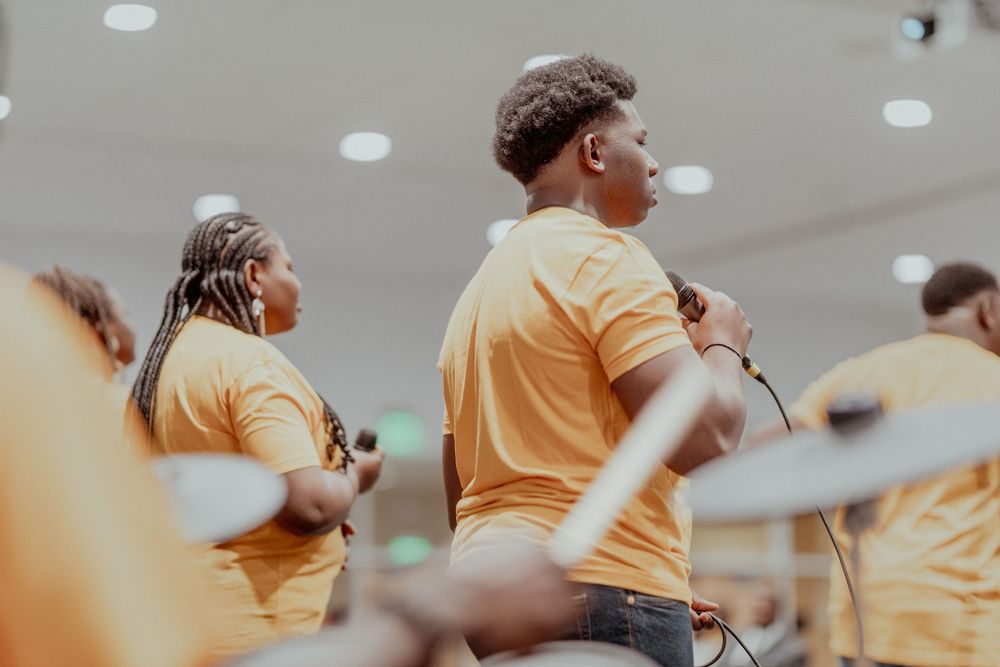 Worship team members in bright yellow shirts lead praise and worship at a church service.