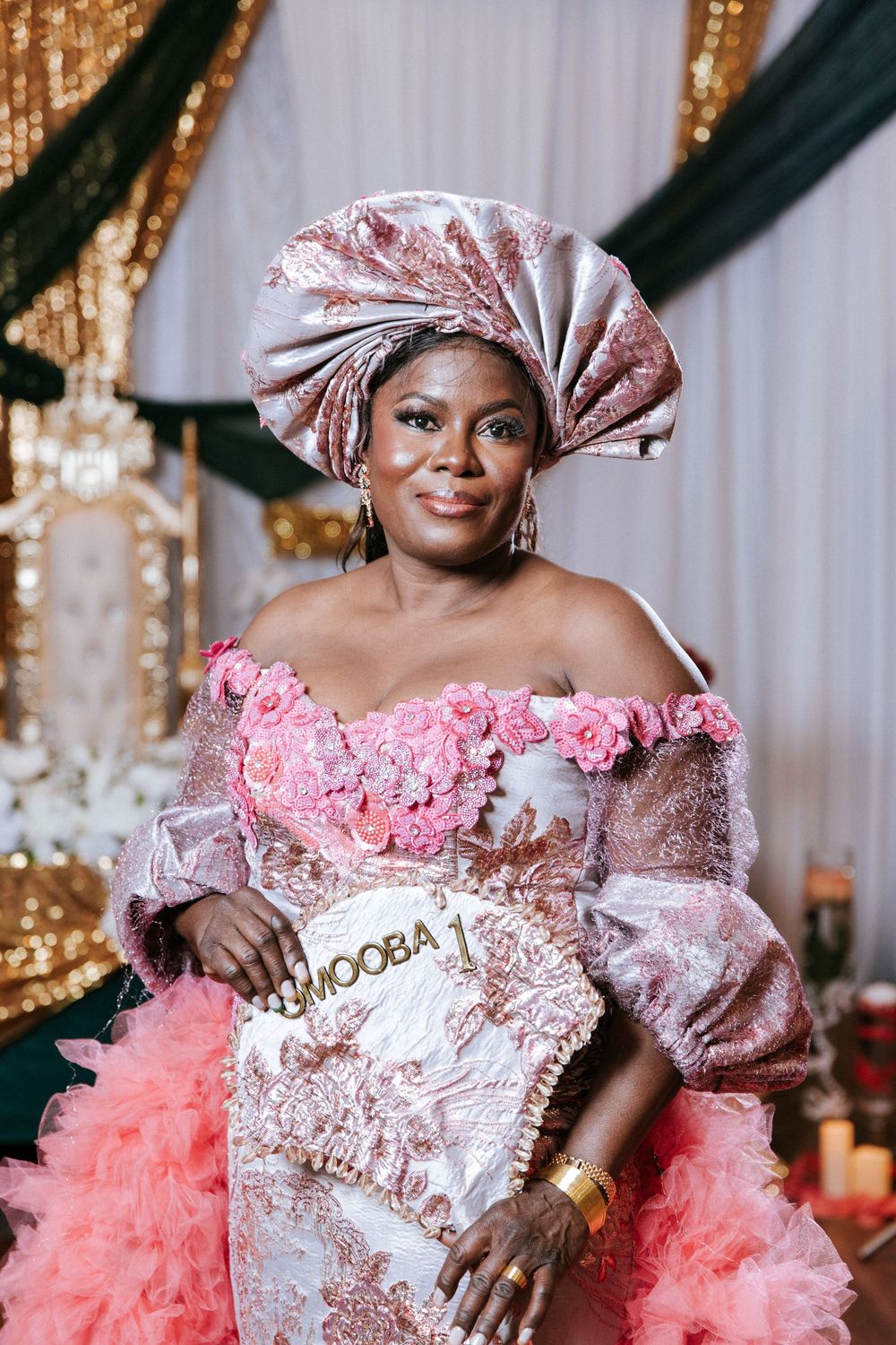 Traditional wedding celebration with ornate pink and white gown featuring floral details and sparkly decor.