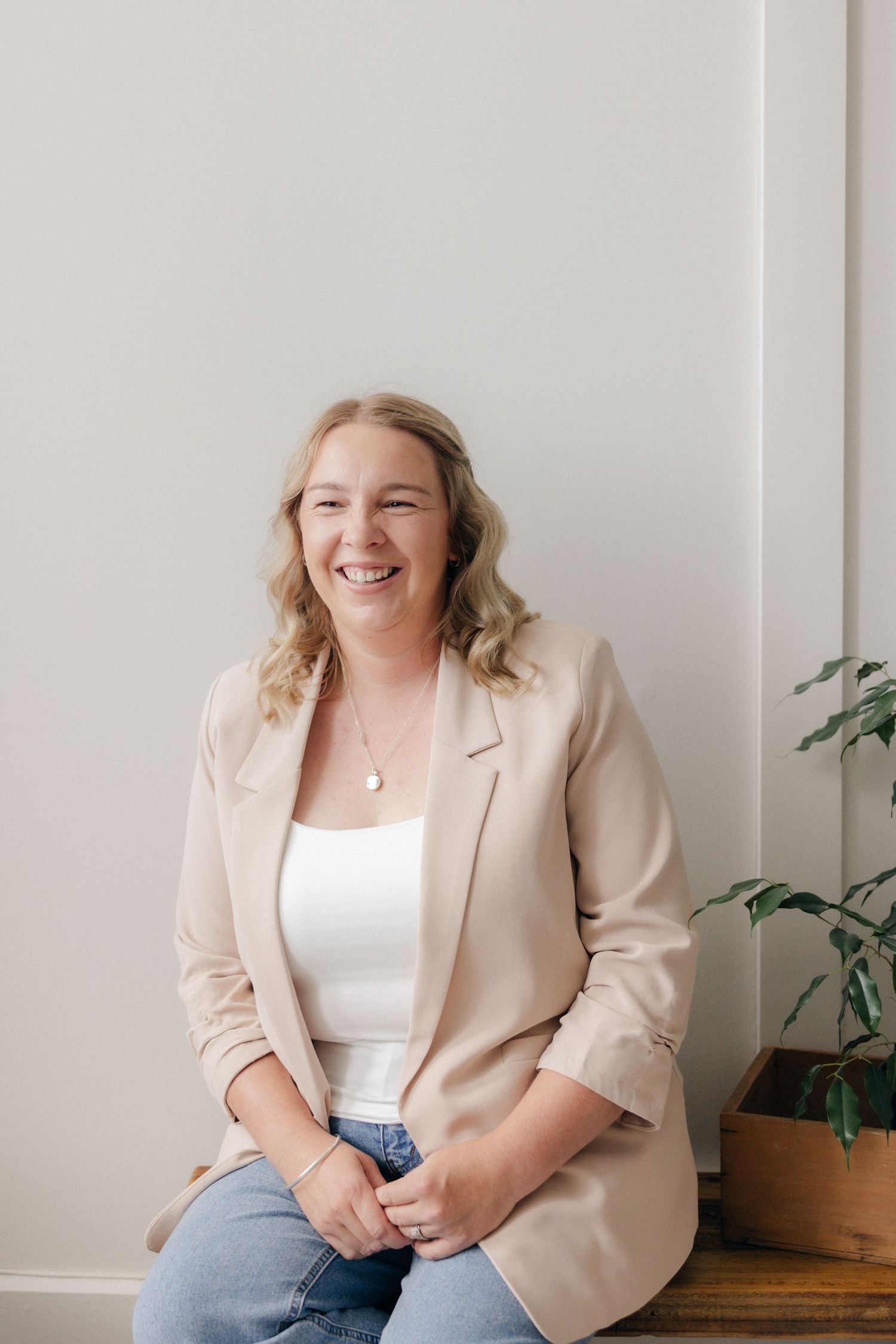 Professional portrait in a white outfit against a modern interior background.