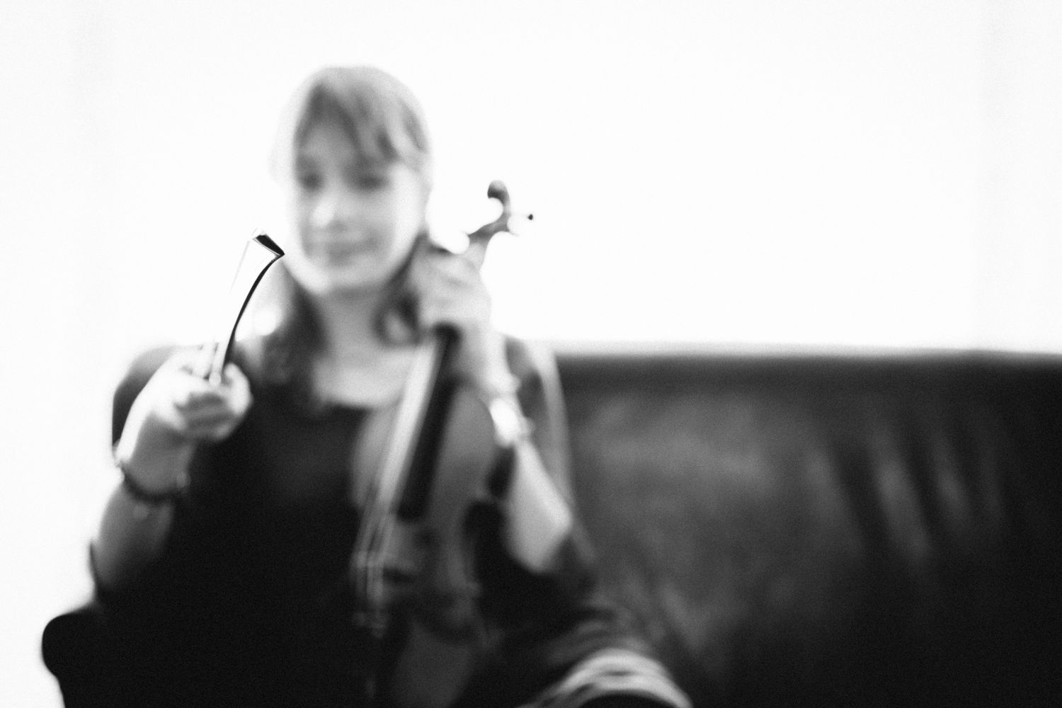 Blurry black and white photo of someone holding a violin.