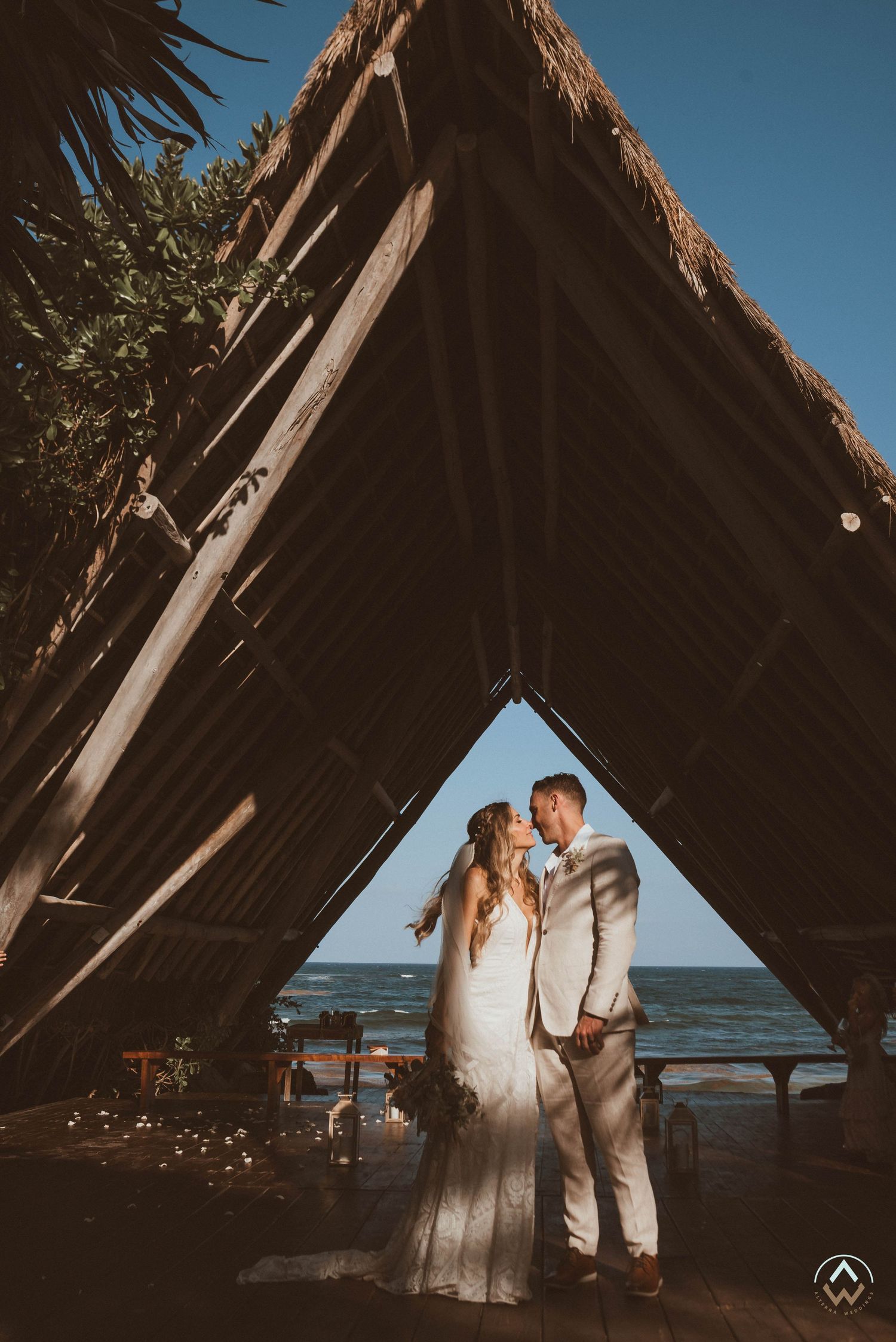 Wedding couple shares intimate moment in wooden beach structure with ocean view, Papaya Playa Tulum Wedding.