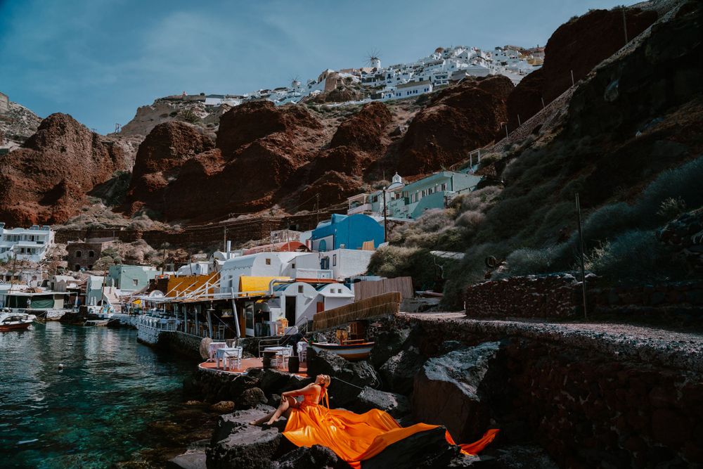 Mediterranean fishing harbor with orange fabric draped over rocky coastline.