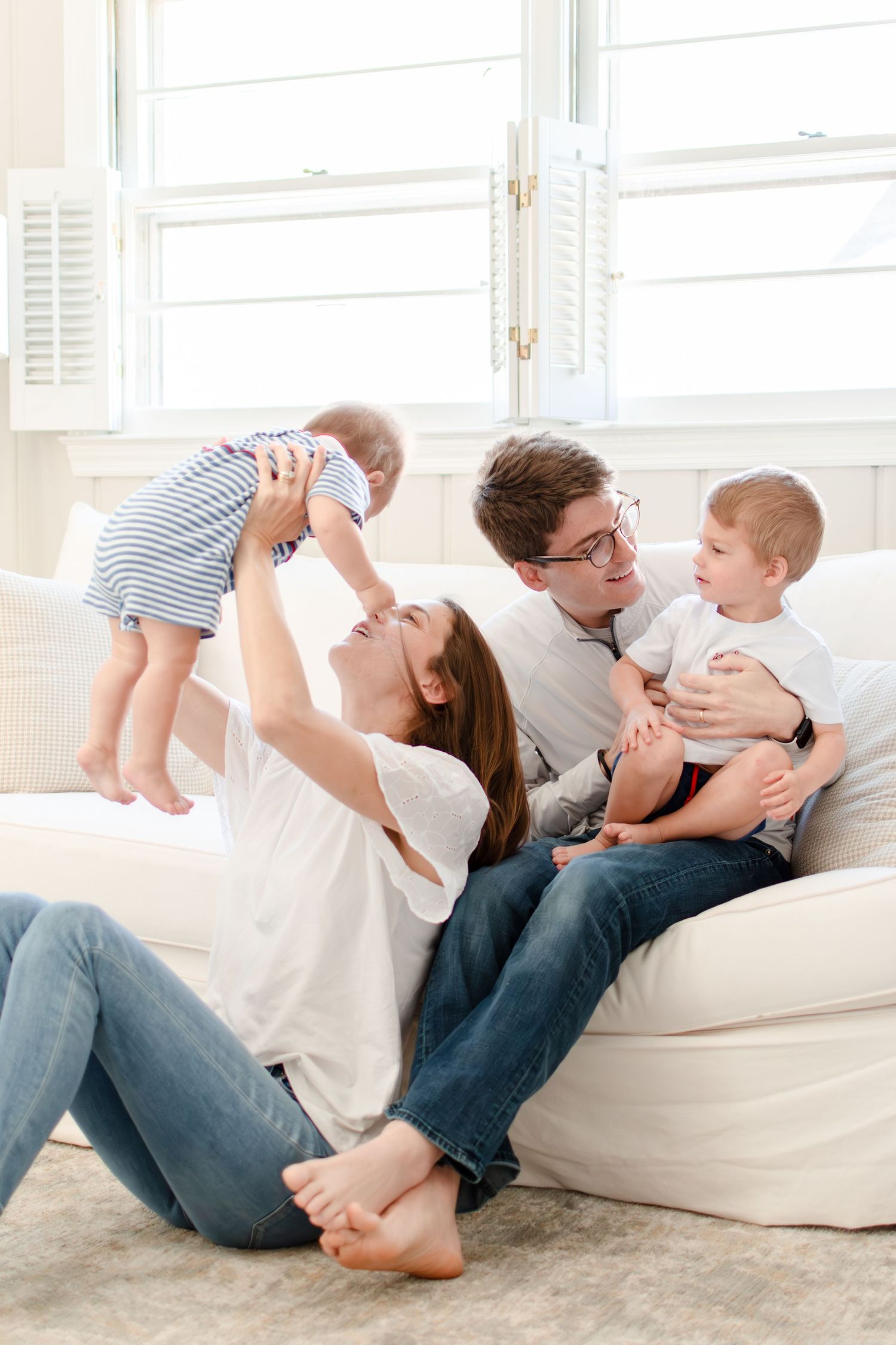 A young Ardmore family playfully snuggles together on the couch in their living room.