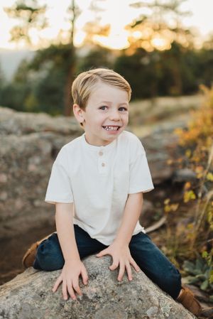 Child posing on a rock during family photo session in the Colorado Mountains. Family photo session in Morrison Colorado.