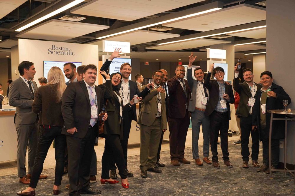 A group of business professionals gathered at a corporate event in an indoor venue with modern lighting fixtures.