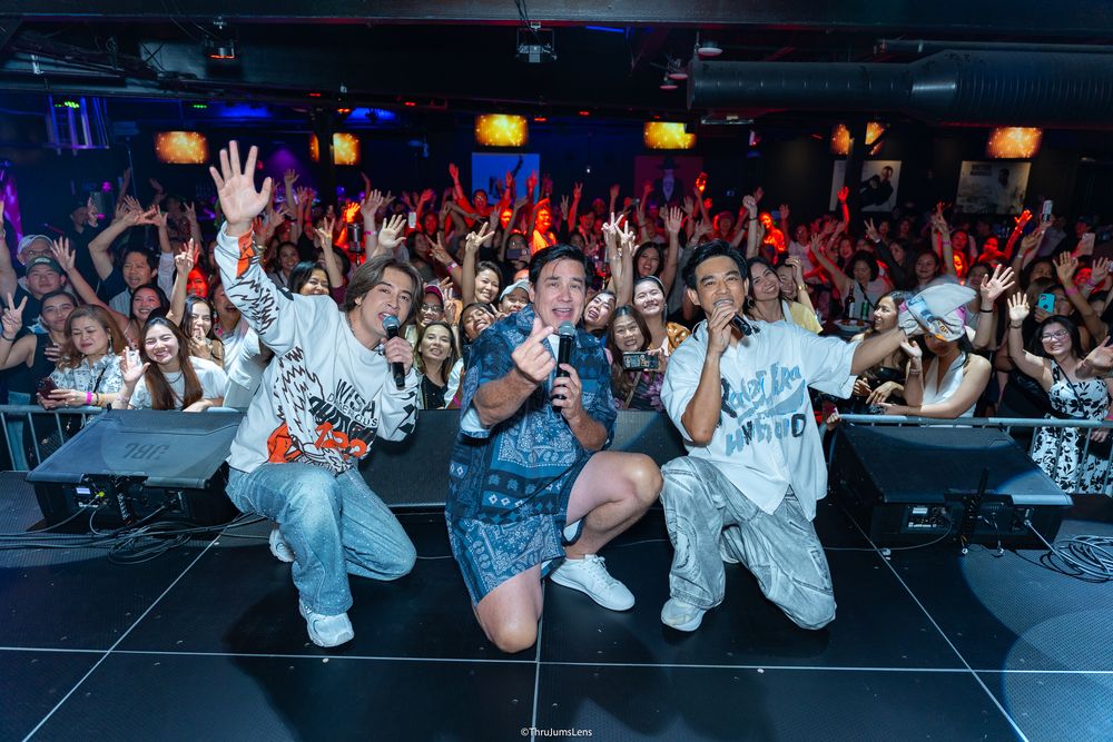 Energetic performers on stage interacting with an enthusiastic crowd at a nightclub with colorful lighting.