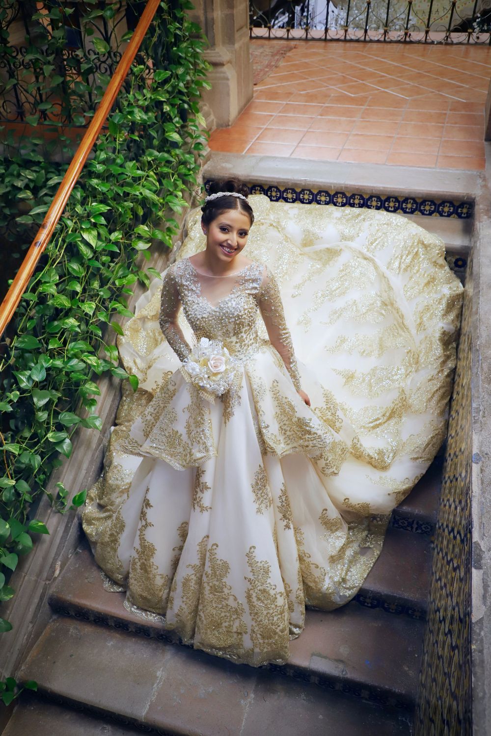 Ornate white and gold wedding dress with elaborate embroidery details in garden setting.